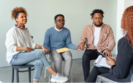 A small group of Black adults sitting together and holding hands in a supportive circle